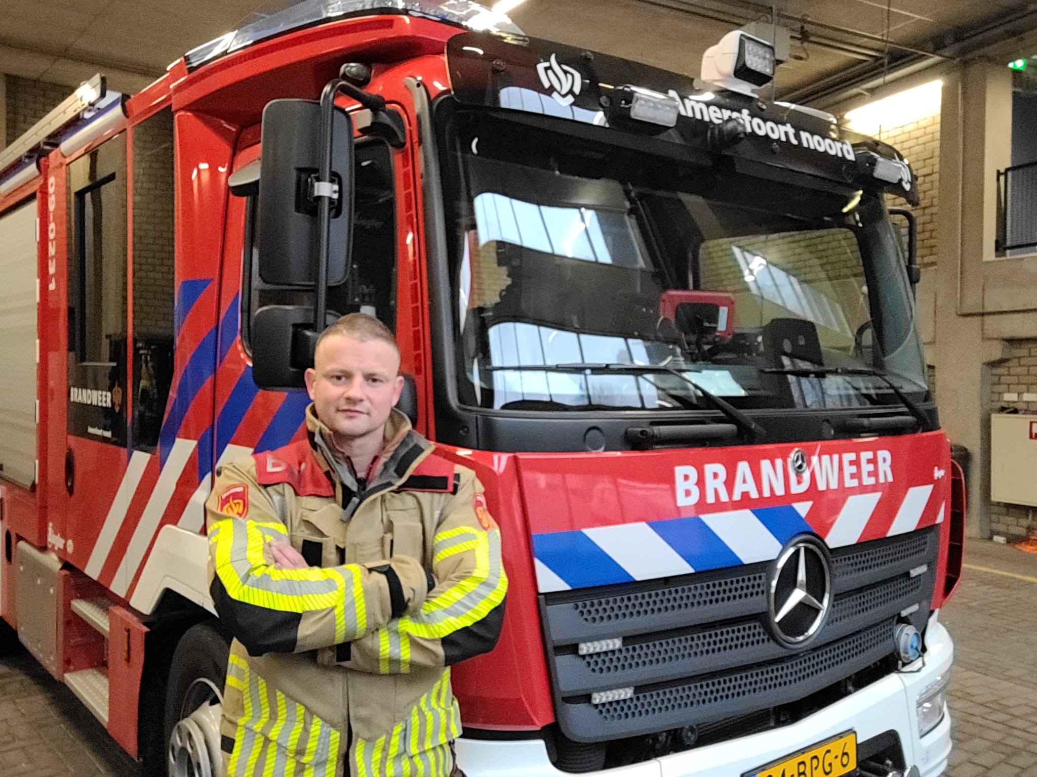 Sander Houtveen in front of a fire truck in his fire fighter uniform