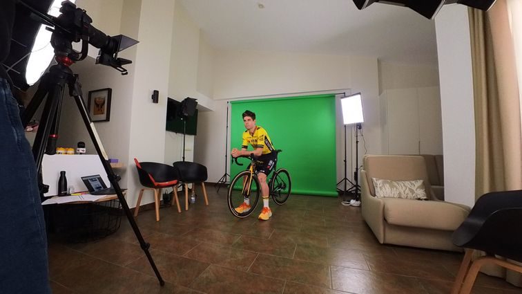 Wout van Aert posing for photo on a bicycle in front of a green screen