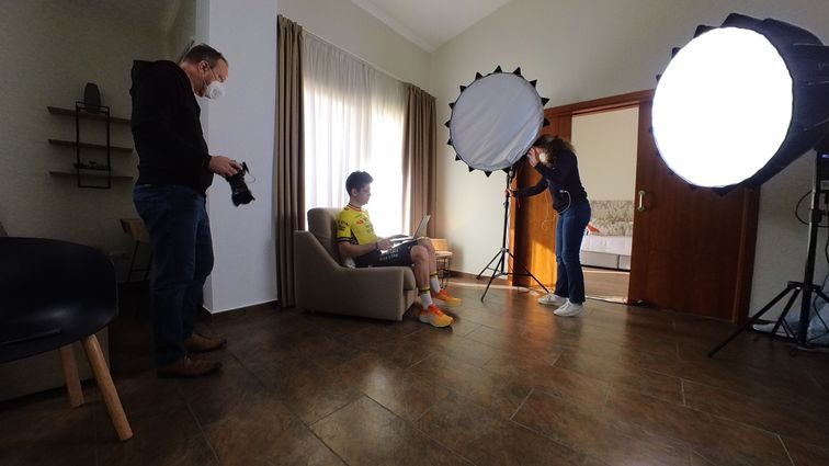 Wout van Aert sitting in a chair and crew fixing lights before an interview