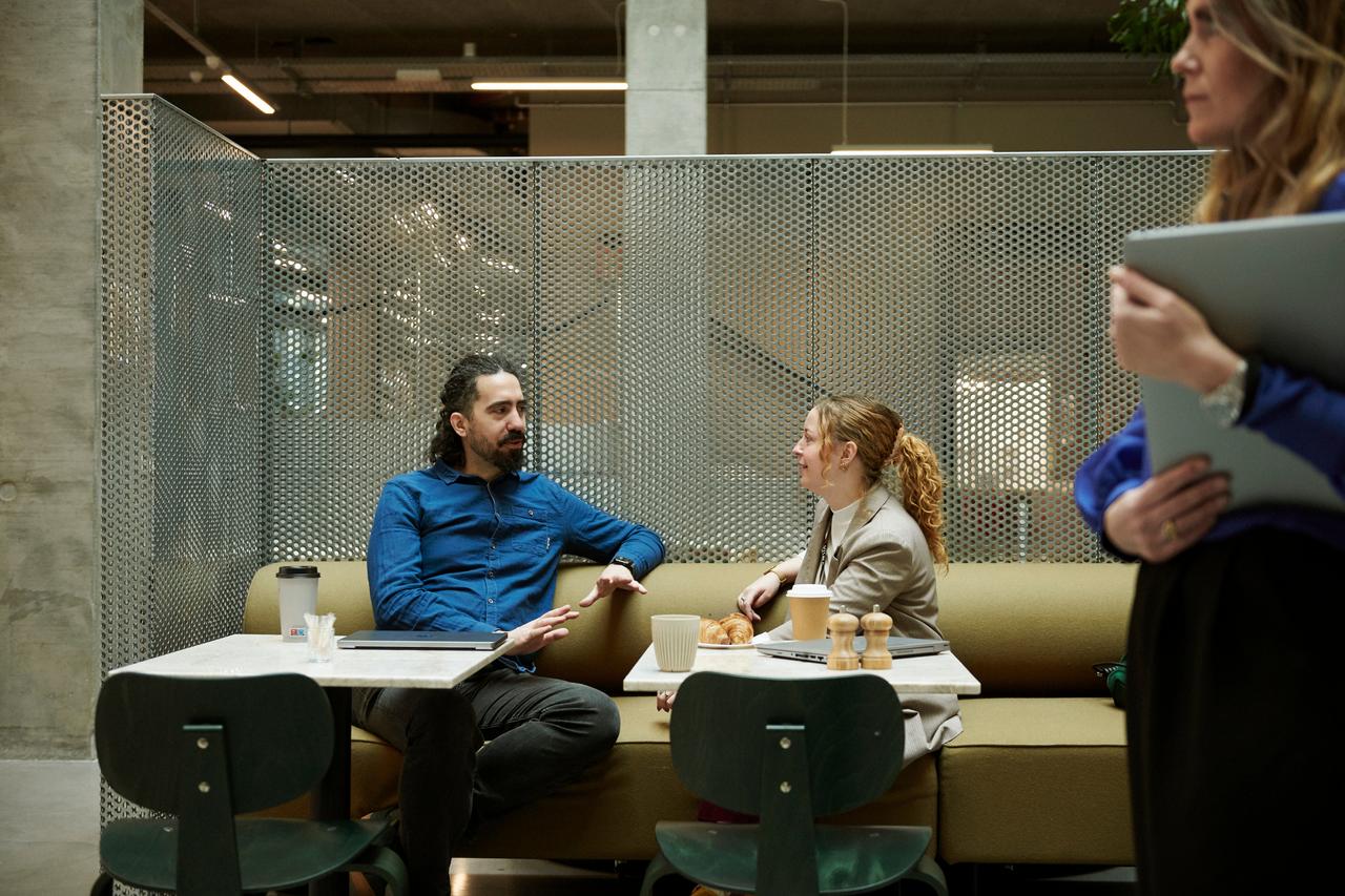 Man and woman colleagues chatting at cafeteria table
