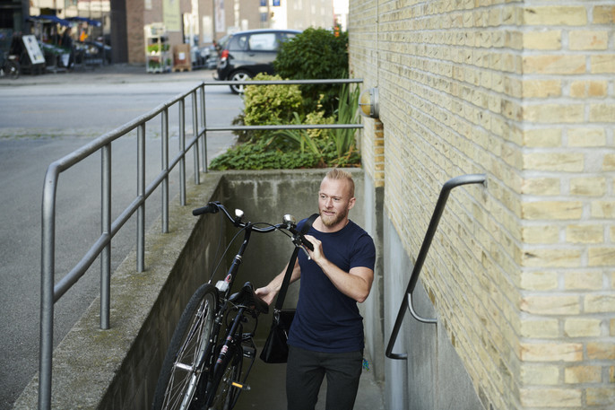 A young business owner carries his bike up the stairs after his morning customer visit.