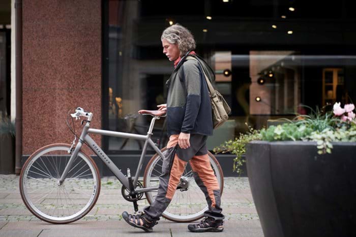 The owner of a small contracting company walks with his bicycle on his way to work.