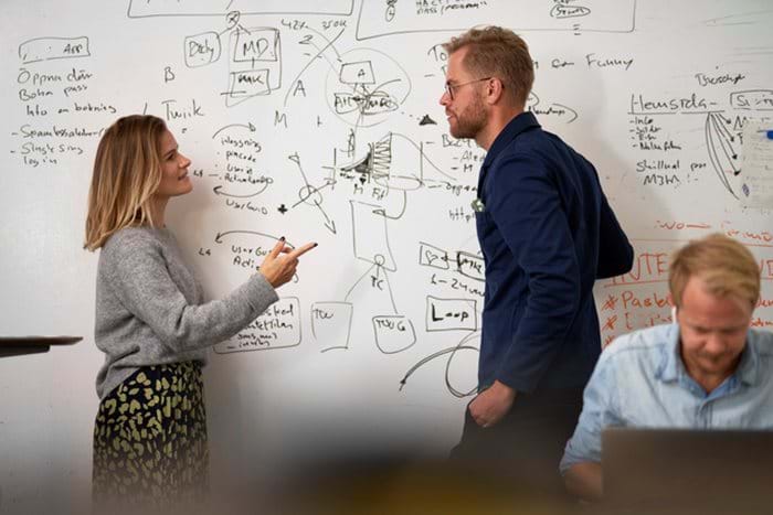 Man and woman discussing in front of a whiteboard