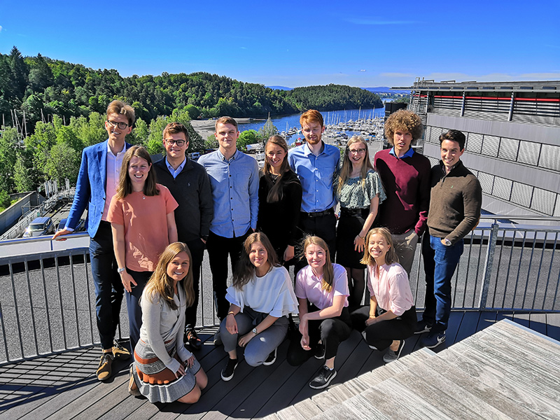 Visma summer interns pose for a photo overlooking the water at Visma's office in Oslo.