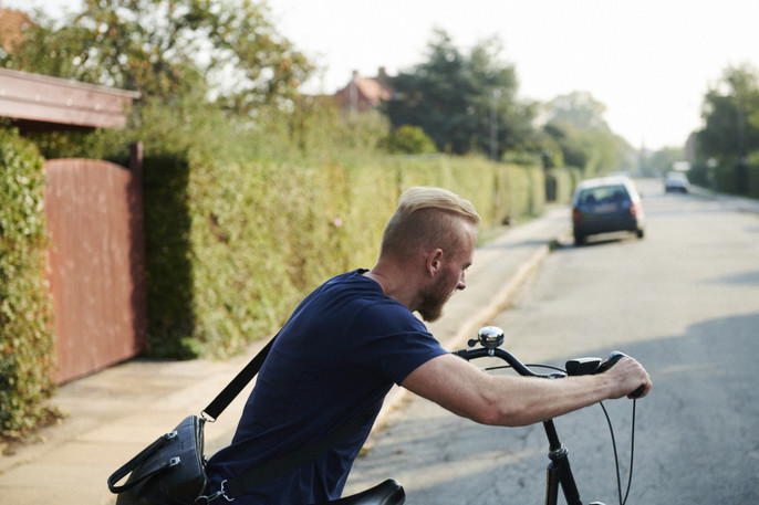 A young male business owner leaves home and cycles to work.