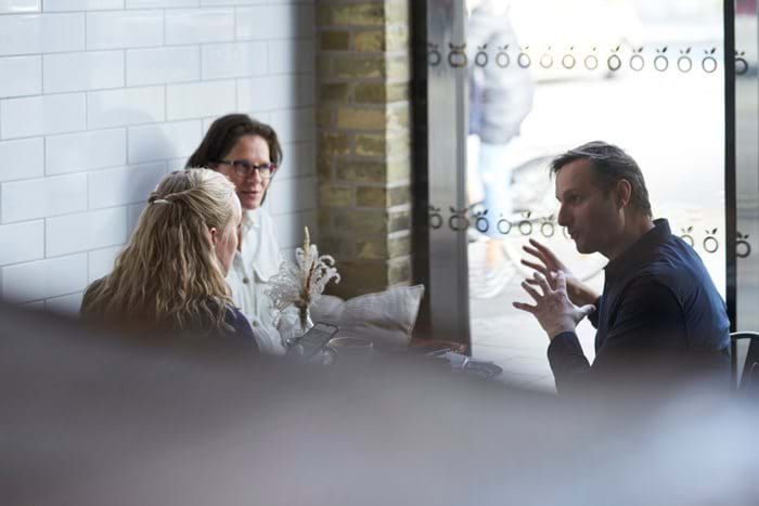 Three colleagues sit in a cafe having an involved discussion.