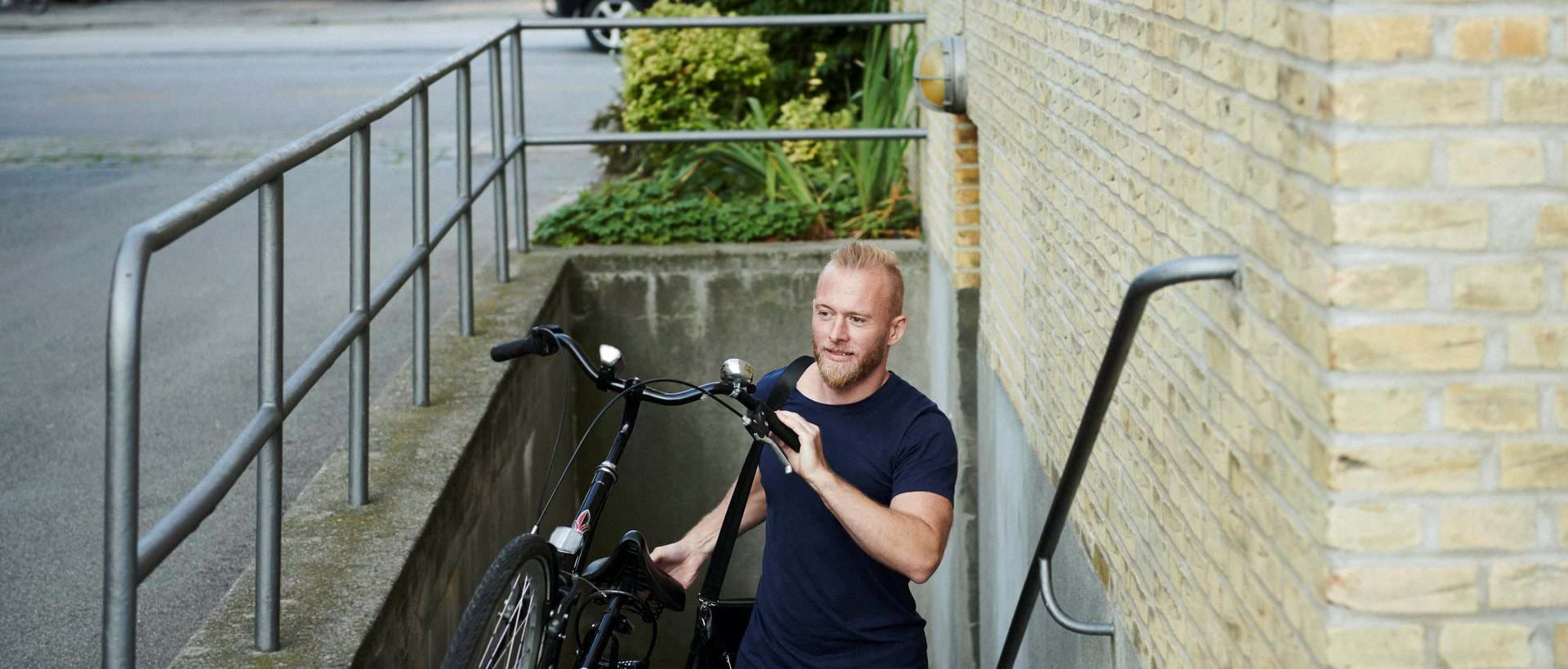 A man carries his bicycle up the stairs as he leaves his basement to go to work.