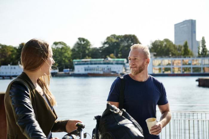 A man and woman having a discussion on a sunny day at the waterfront.