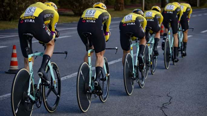 A line of cyclists flies down the road wearing Team Jumbo-Visma attire.